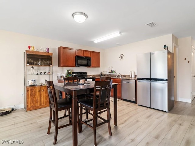 kitchen featuring sink, light hardwood / wood-style flooring, and black appliances