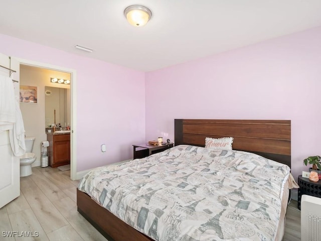 bedroom with ensuite bathroom, sink, and light hardwood / wood-style floors