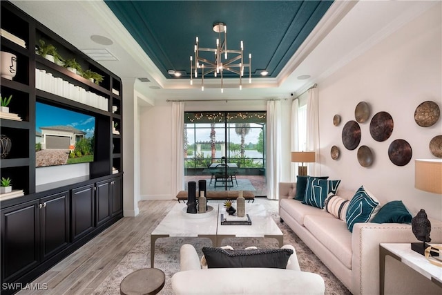 living area with visible vents, a raised ceiling, crown molding, light wood-type flooring, and a chandelier