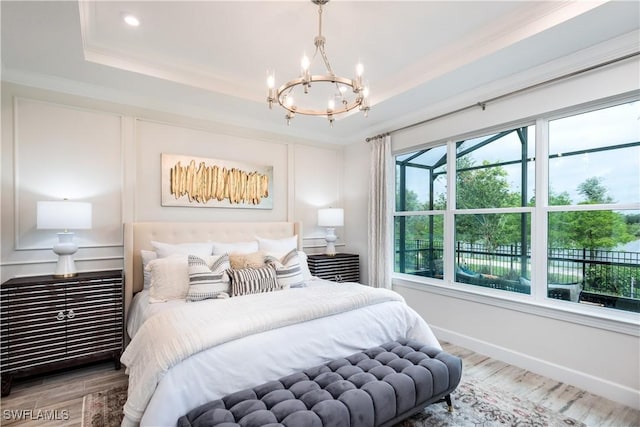 bedroom with wood finished floors, a raised ceiling, and crown molding