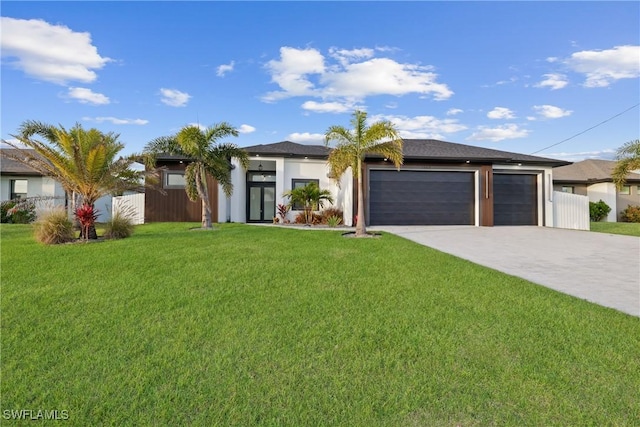 prairie-style home with a front yard, fence, driveway, stucco siding, and a garage