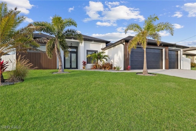 view of front of property featuring a front lawn, fence, stucco siding, driveway, and an attached garage