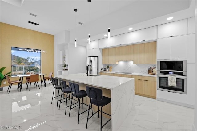 kitchen featuring tasteful backsplash, appliances with stainless steel finishes, marble finish floor, modern cabinets, and a sink