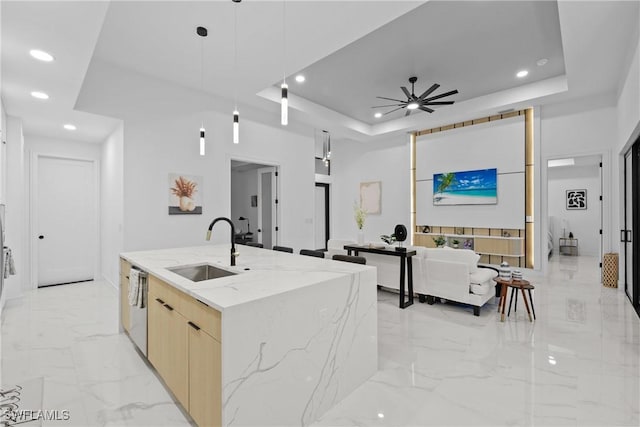 kitchen with marble finish floor, modern cabinets, a raised ceiling, a ceiling fan, and a sink