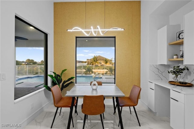 dining space featuring marble finish floor, baseboards, and an inviting chandelier