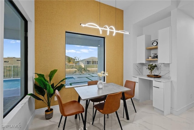 dining room with an inviting chandelier, baseboards, and marble finish floor