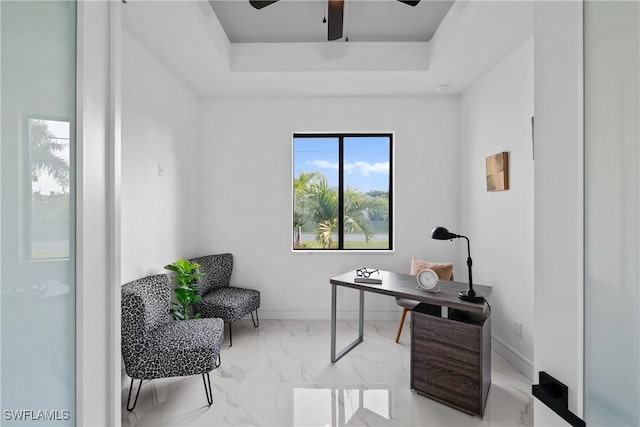 office area with a raised ceiling, a ceiling fan, marble finish floor, and baseboards