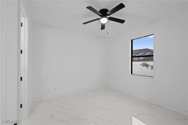 empty room featuring a ceiling fan, baseboards, and marble finish floor