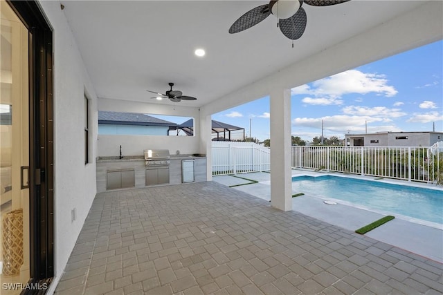 view of pool with a patio, exterior kitchen, a fenced backyard, and ceiling fan