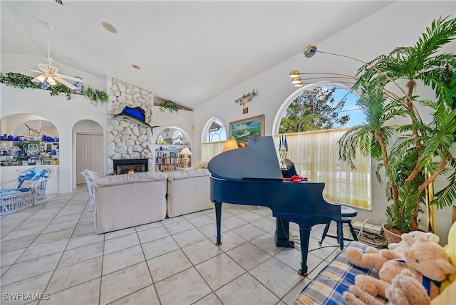 miscellaneous room featuring light tile patterned flooring, ceiling fan, lofted ceiling, and a fireplace