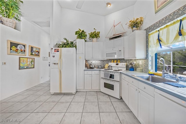 kitchen featuring light tile patterned flooring, sink, white appliances, decorative backsplash, and white cabinets