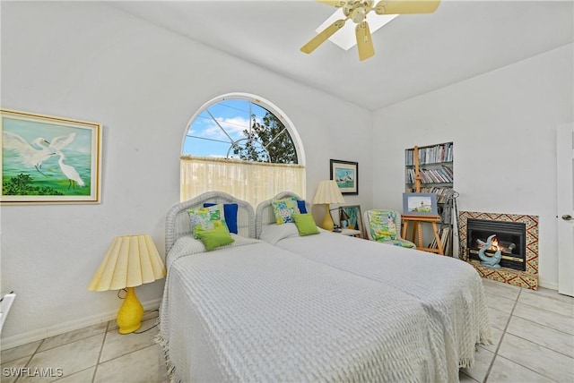 bedroom with light tile patterned flooring, ceiling fan, lofted ceiling, and a tiled fireplace