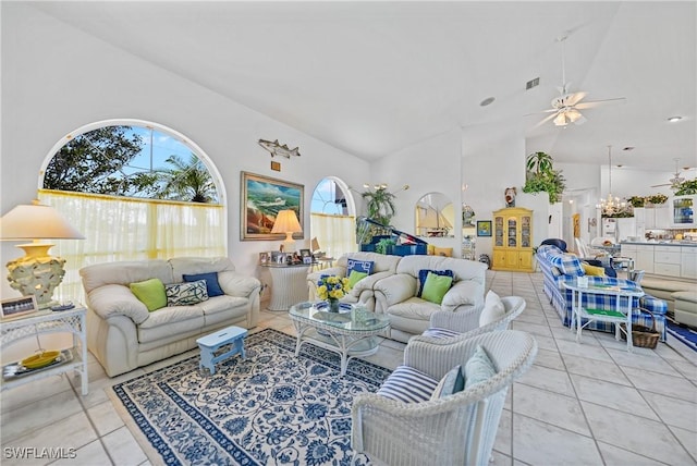 tiled living room with ceiling fan with notable chandelier and high vaulted ceiling