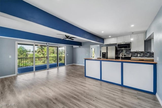 kitchen featuring appliances with stainless steel finishes, light hardwood / wood-style flooring, decorative backsplash, and white cabinets