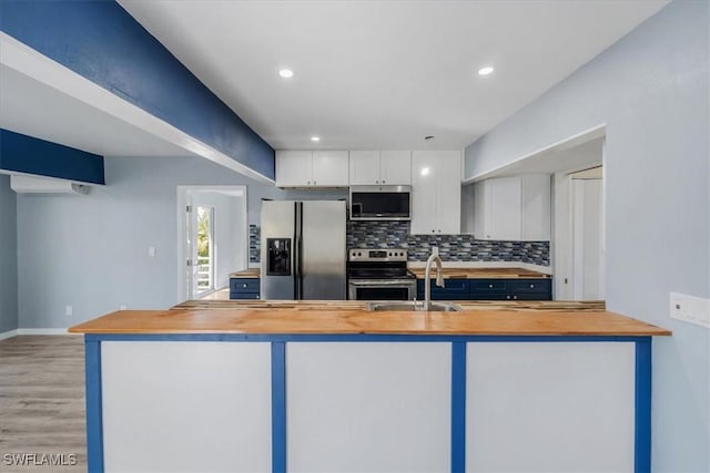 kitchen with sink, butcher block countertops, white cabinetry, appliances with stainless steel finishes, and backsplash