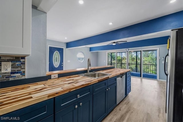 kitchen featuring butcher block countertops, sink, backsplash, stainless steel appliances, and white cabinets