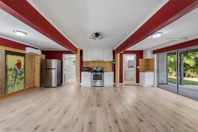 kitchen with light hardwood / wood-style flooring, appliances with stainless steel finishes, a wall unit AC, tasteful backsplash, and white cabinets