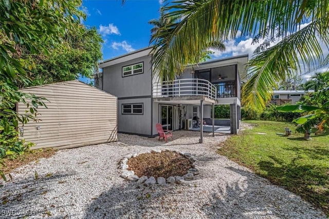 back of property featuring ceiling fan, a yard, a balcony, and a patio