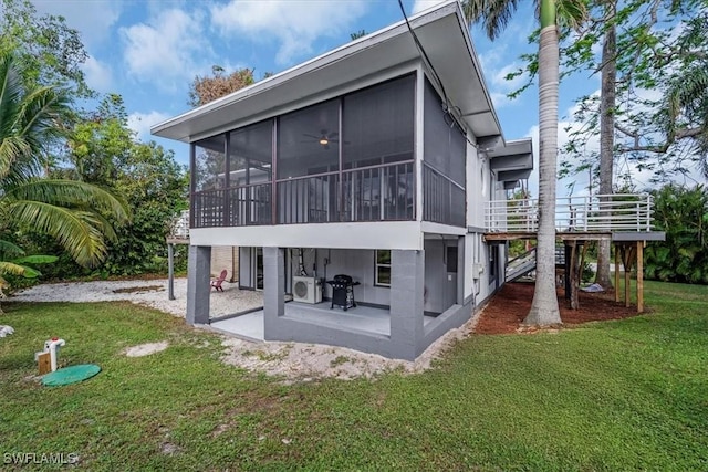 back of property with a sunroom, a lawn, and a patio area