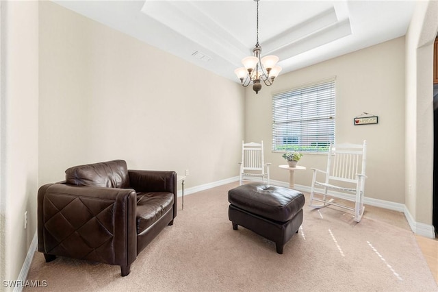 living area with an inviting chandelier, a raised ceiling, and carpet