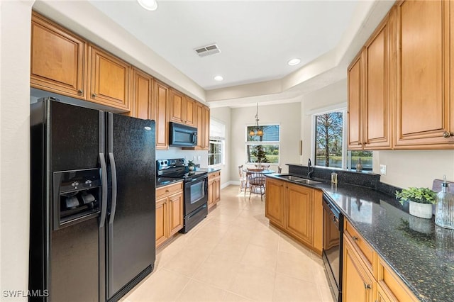 kitchen with pendant lighting, sink, a tray ceiling, black appliances, and dark stone counters