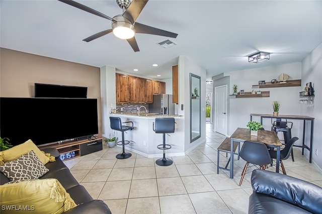 living room featuring light tile patterned flooring, sink, and ceiling fan