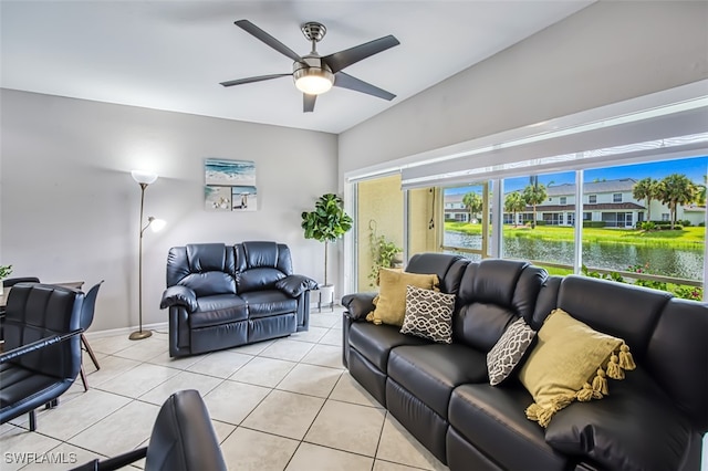 tiled living room featuring ceiling fan and a water view