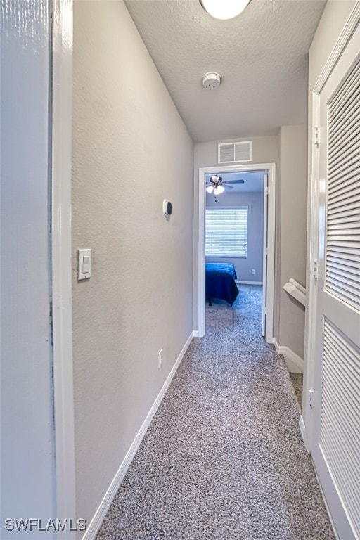 corridor featuring light colored carpet and a textured ceiling