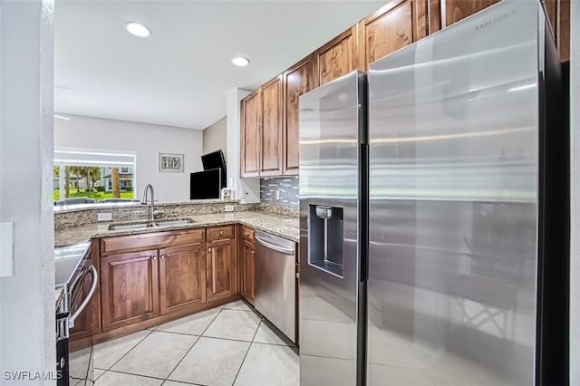 kitchen with sink, light stone counters, tasteful backsplash, light tile patterned floors, and stainless steel appliances