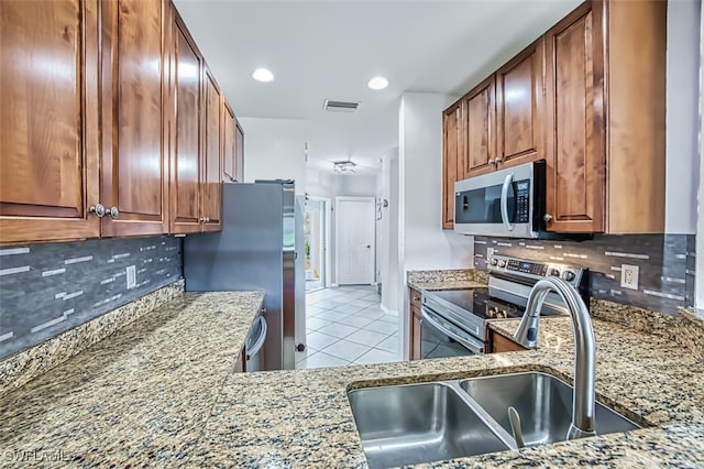 kitchen with stainless steel appliances, sink, and light stone counters