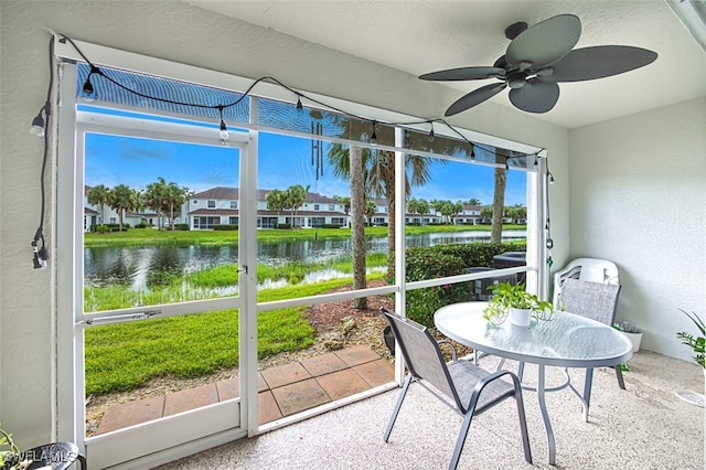 sunroom featuring a water view and ceiling fan