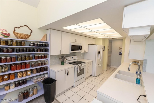 kitchen featuring light tile patterned floors, white appliances, a sink, light countertops, and backsplash