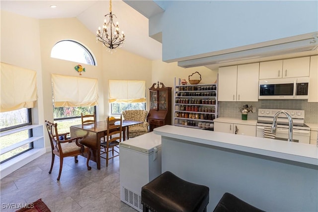 kitchen featuring decorative light fixtures, light countertops, decorative backsplash, an inviting chandelier, and white appliances