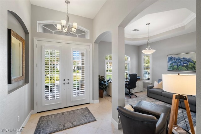 entrance foyer with a tray ceiling, a wealth of natural light, light tile patterned floors, and french doors