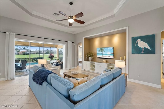 living room featuring ornamental molding, light tile patterned floors, and a tray ceiling