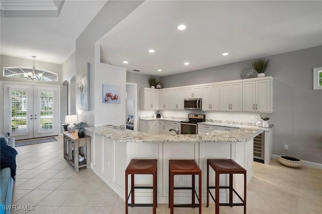 kitchen with light stone counters, appliances with stainless steel finishes, a breakfast bar, and white cabinets