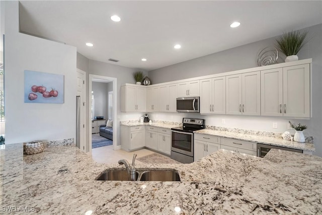 kitchen featuring white cabinetry, sink, wine cooler, stainless steel appliances, and light stone countertops