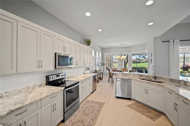 kitchen with sink, appliances with stainless steel finishes, a healthy amount of sunlight, white cabinets, and decorative light fixtures