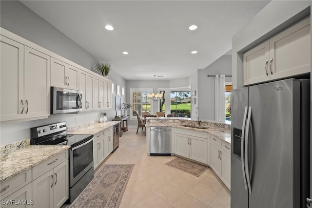 kitchen with sink, light stone counters, decorative light fixtures, appliances with stainless steel finishes, and white cabinets