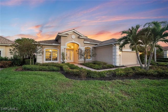 mediterranean / spanish-style house with a garage and a lawn