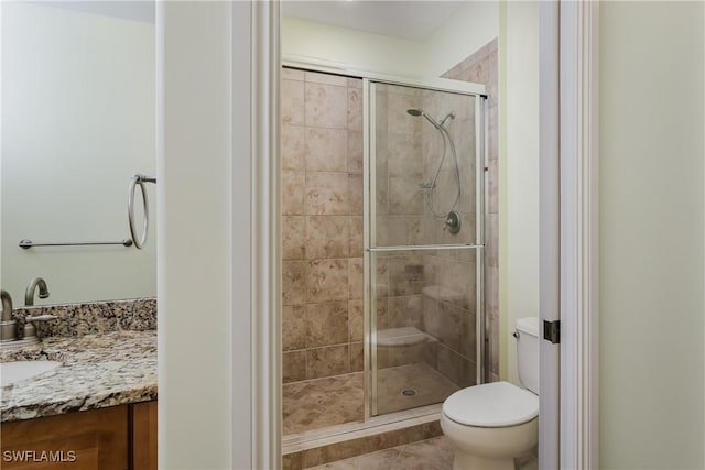 bathroom with toilet, a stall shower, and vanity