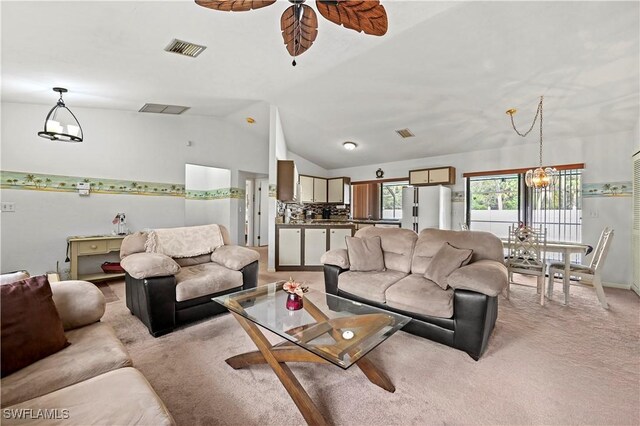 living room featuring ceiling fan with notable chandelier, vaulted ceiling, and light colored carpet