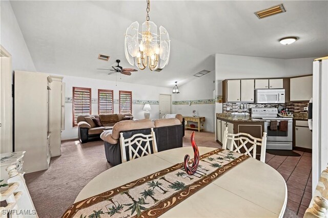 dining room featuring ceiling fan with notable chandelier, vaulted ceiling, and dark colored carpet