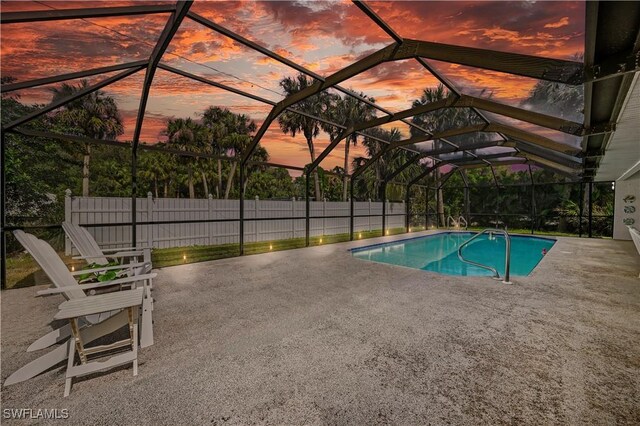 pool at dusk featuring a patio and a lanai