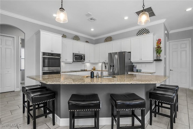 kitchen with white cabinetry, a kitchen bar, a large island with sink, and appliances with stainless steel finishes