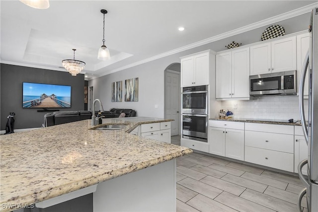 kitchen with pendant lighting, stainless steel appliances, sink, and white cabinets