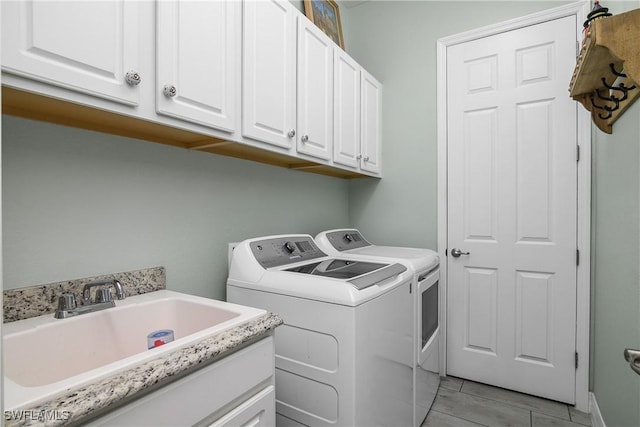 laundry room with sink, washing machine and dryer, and cabinets