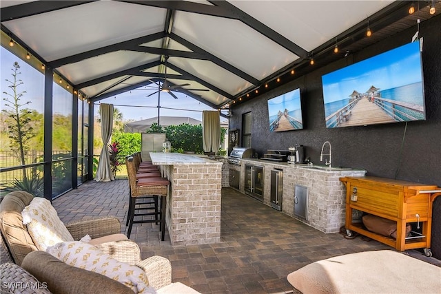 view of patio / terrace with a grill, a lanai, an outdoor kitchen, and an outdoor wet bar