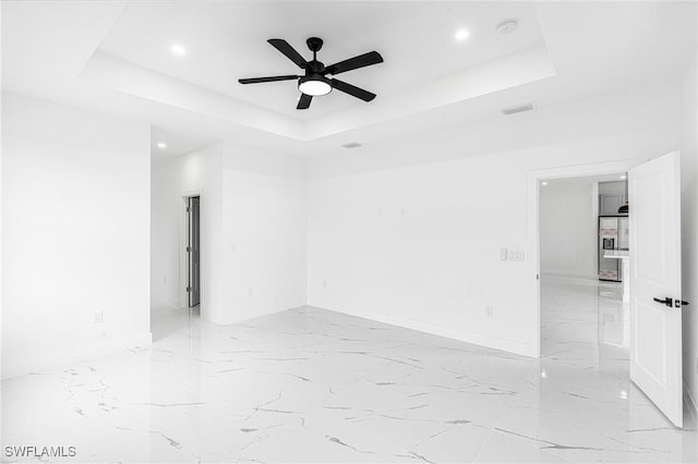 unfurnished room with ceiling fan and a raised ceiling