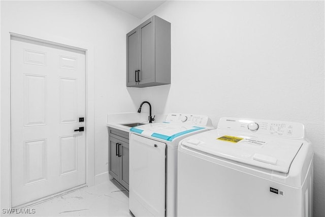 clothes washing area with cabinets, washing machine and dryer, and sink